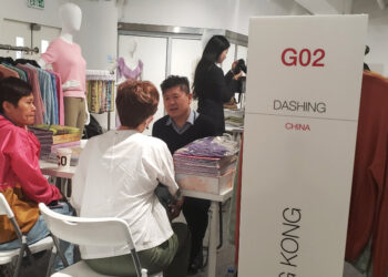 A group of people sitting at a table in a clothing store.